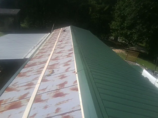 Old rusted panels beside newly installed green metal roofing — Wind Damage Roof Repair by Roofing Brothers in Long Beach